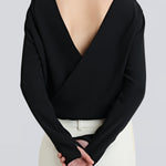 A person wearing a black, backless, cross-over shirt with long sleeves and a V-neckline, by sener besim