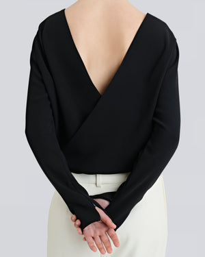 A person wearing a black, backless, cross-over shirt with long sleeves and a V-neckline, by sener besim