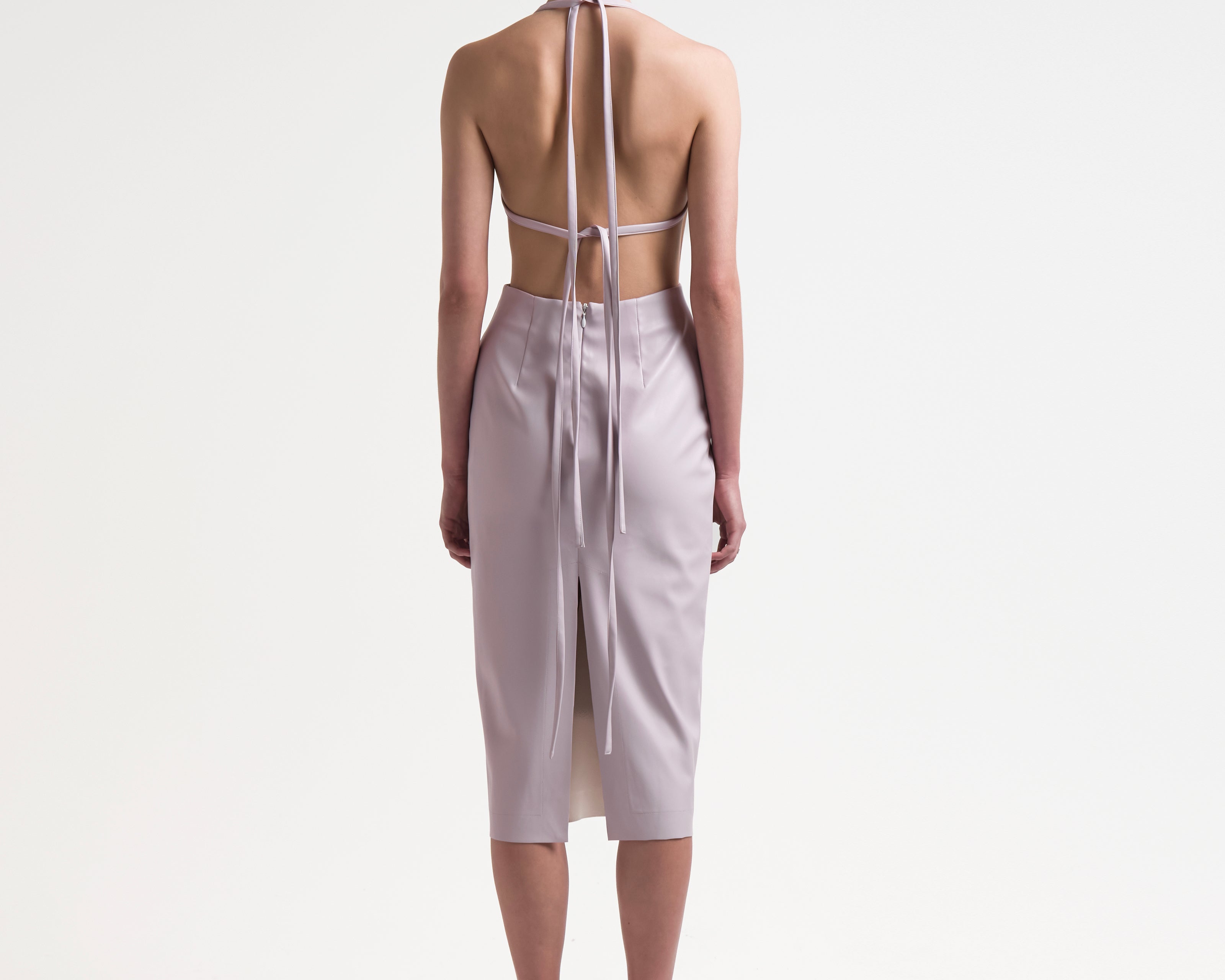 model wearing backless vegan leather dress with ties and a mid length by sener besim