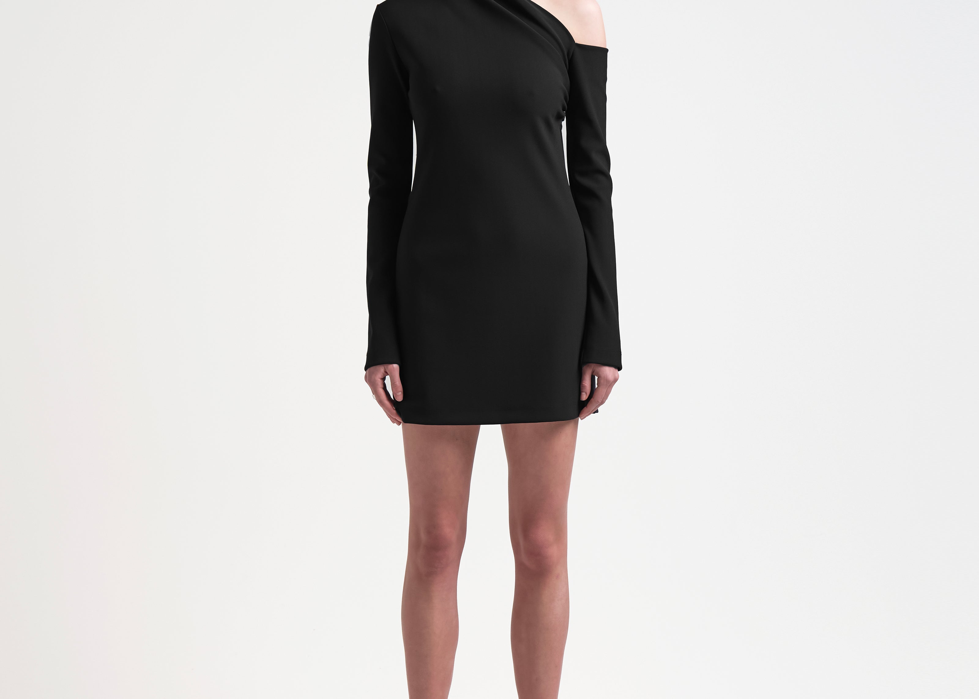 A model wearing a black asymmetric neckline, long-sleeved, mini-length bonded dress with a sharp, angular design.
