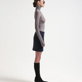 side view of model wearing a sener besim high-waisted, knee-length bonded mini skirt in navy