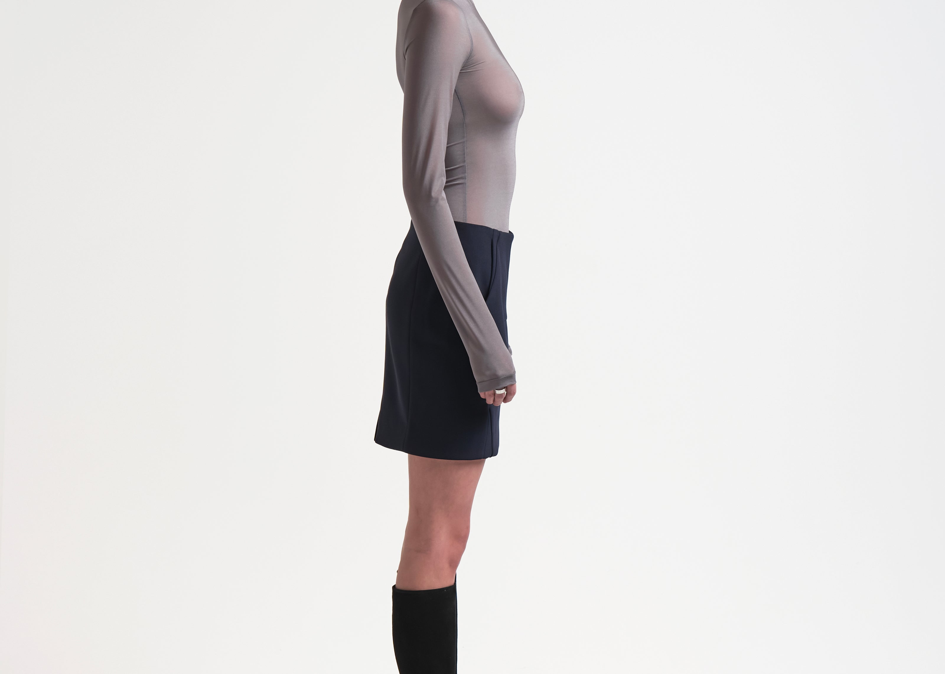 side view of model wearing a sener besim high-waisted, knee-length bonded mini skirt in navy