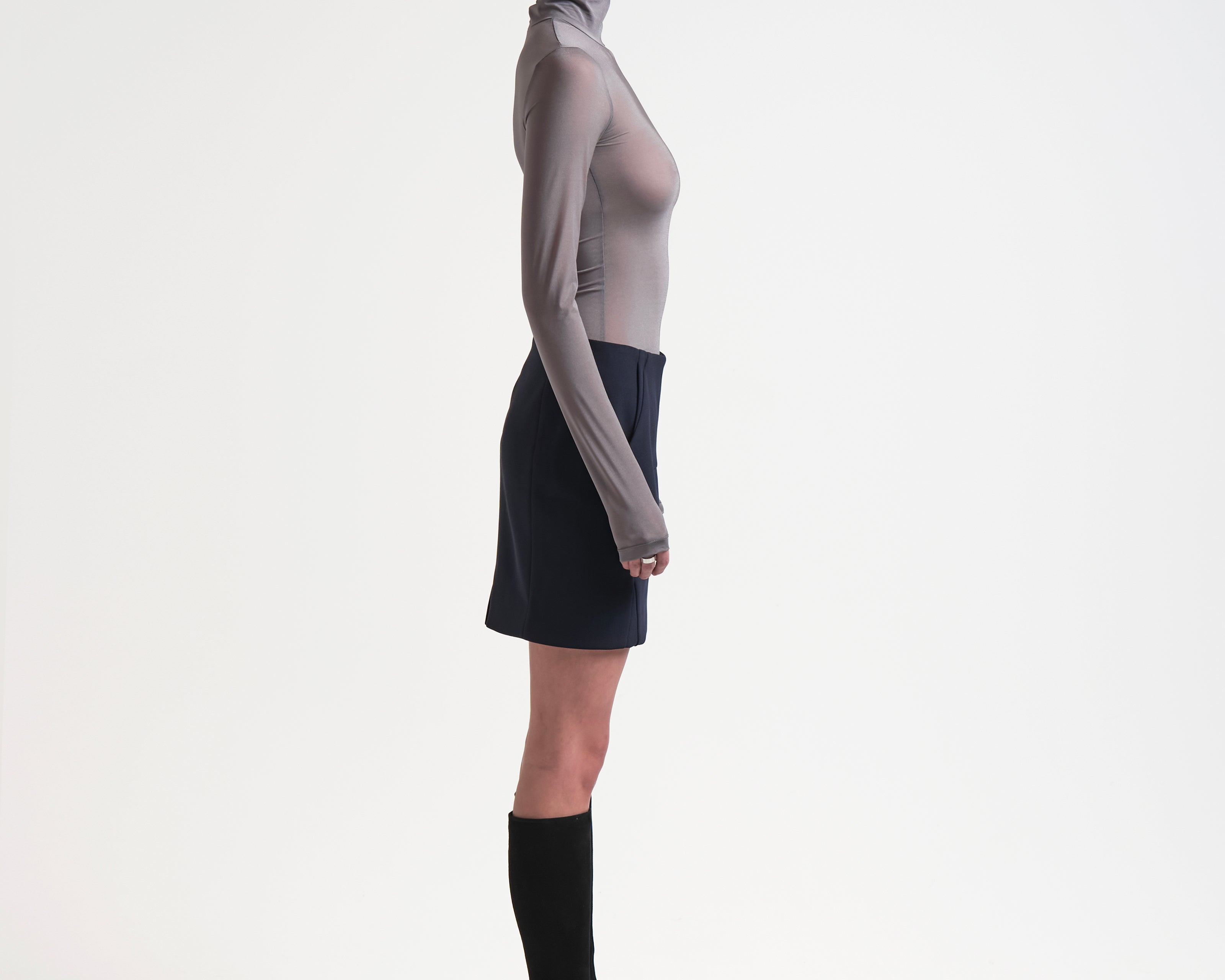 side view of model wearing a sener besim high-waisted, knee-length bonded mini skirt in navy