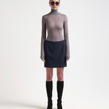A model wearing a high-waisted, knee-length bonded mini skirt in navy colour by sener besim