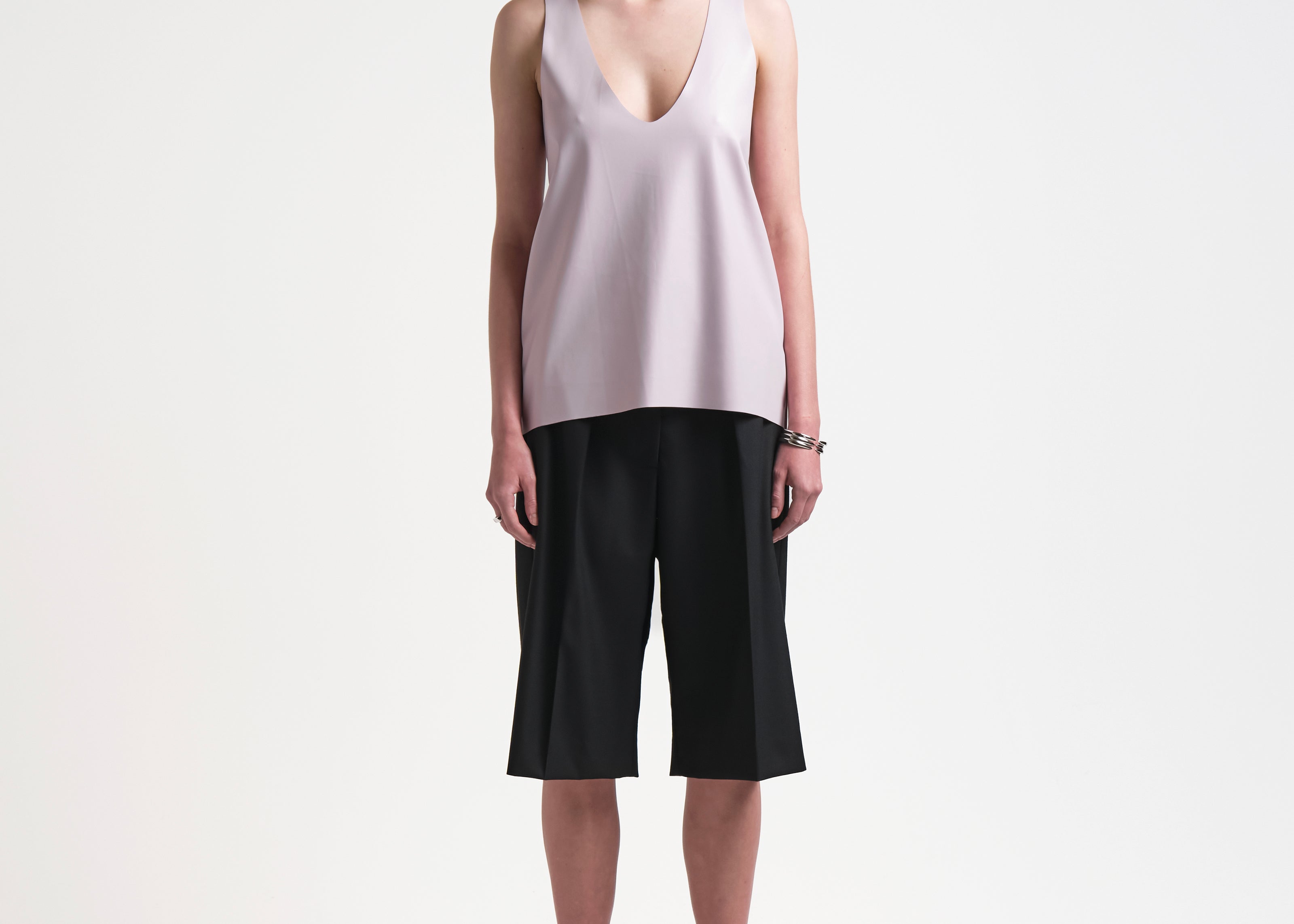 A model wearing a light pink sleeveless tank top with a deep curved neckline by sener besim