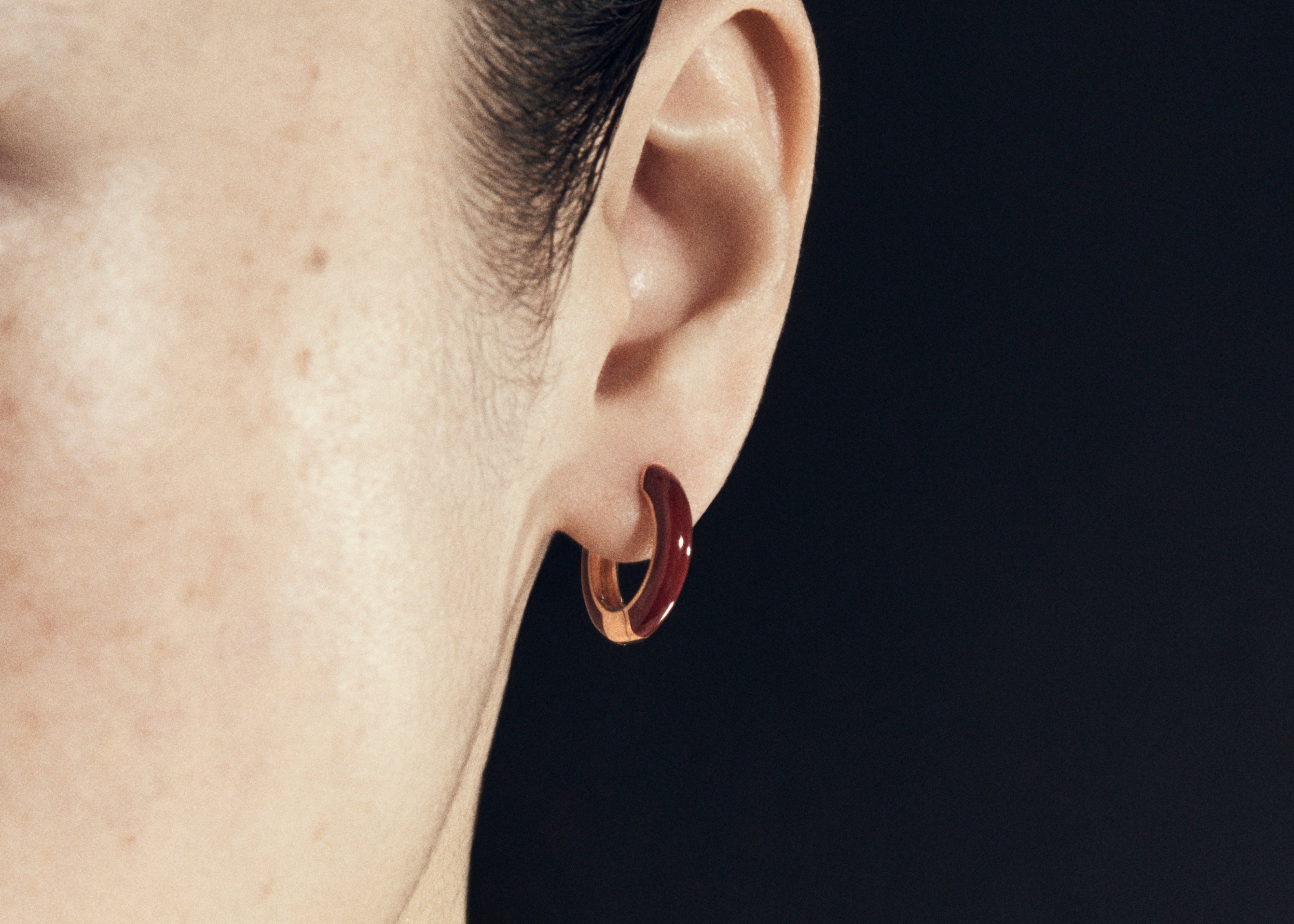 Şener Besim Enamel Huggie burgundy gold worn on ear, editorial shot