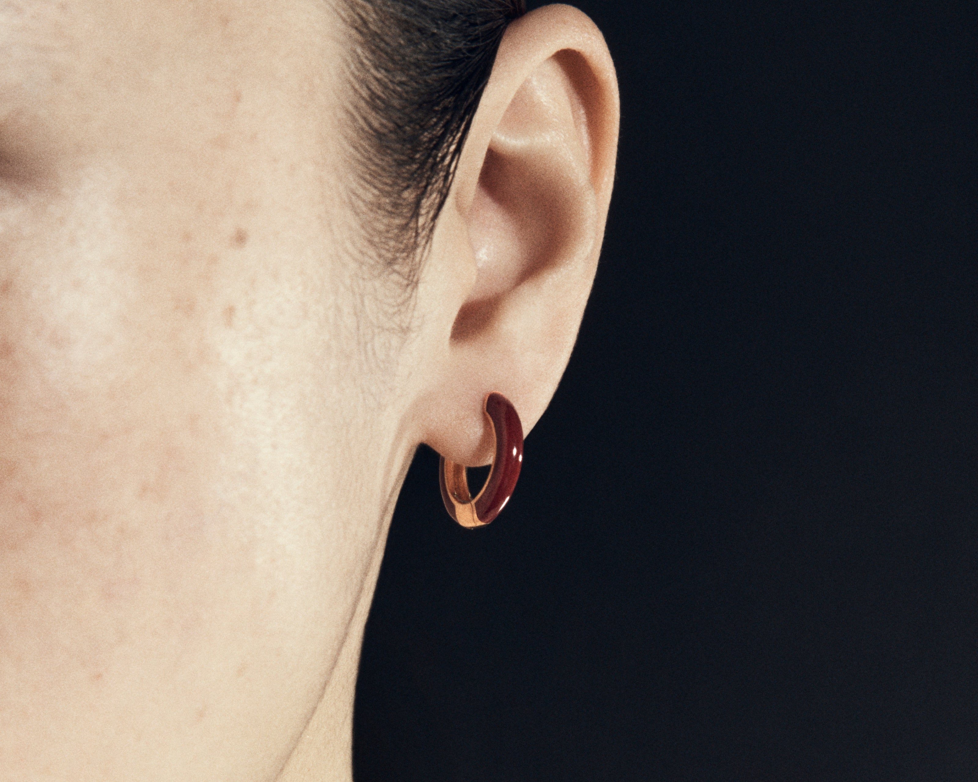 Şener Besim Enamel Huggie burgundy gold worn on ear, editorial shot
