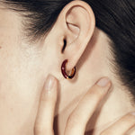 Şener Besim Enamel Huggie burgundy and gold plating, worn close up on ear
