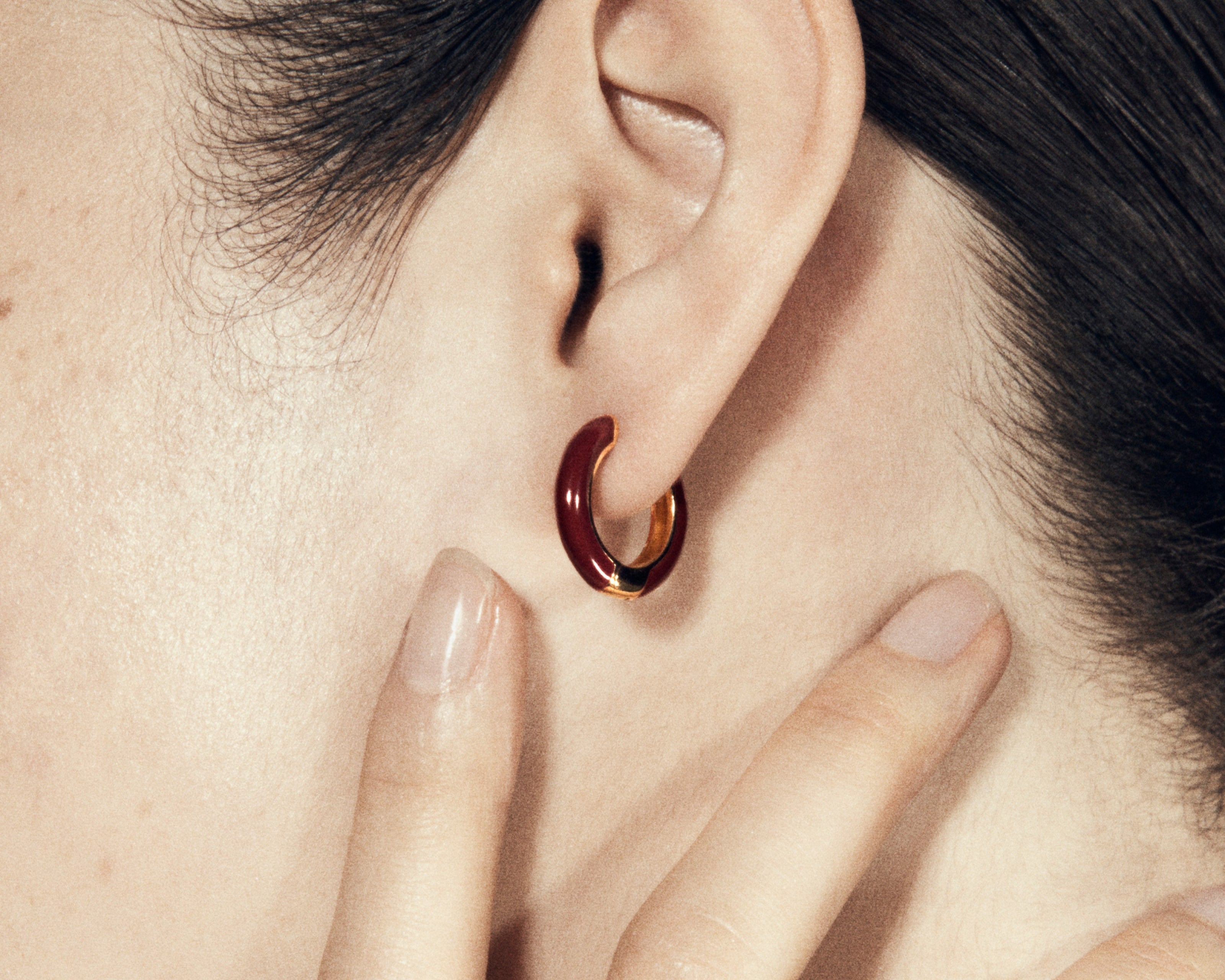 Şener Besim Enamel Huggie burgundy and gold plating, worn close up on ear