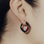 Close up of Şener Besim burgundy enamel hoop earring on ear — side view