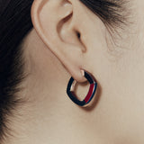 Close up of Şener Besim burgundy enamel hoop earring on ear — side view