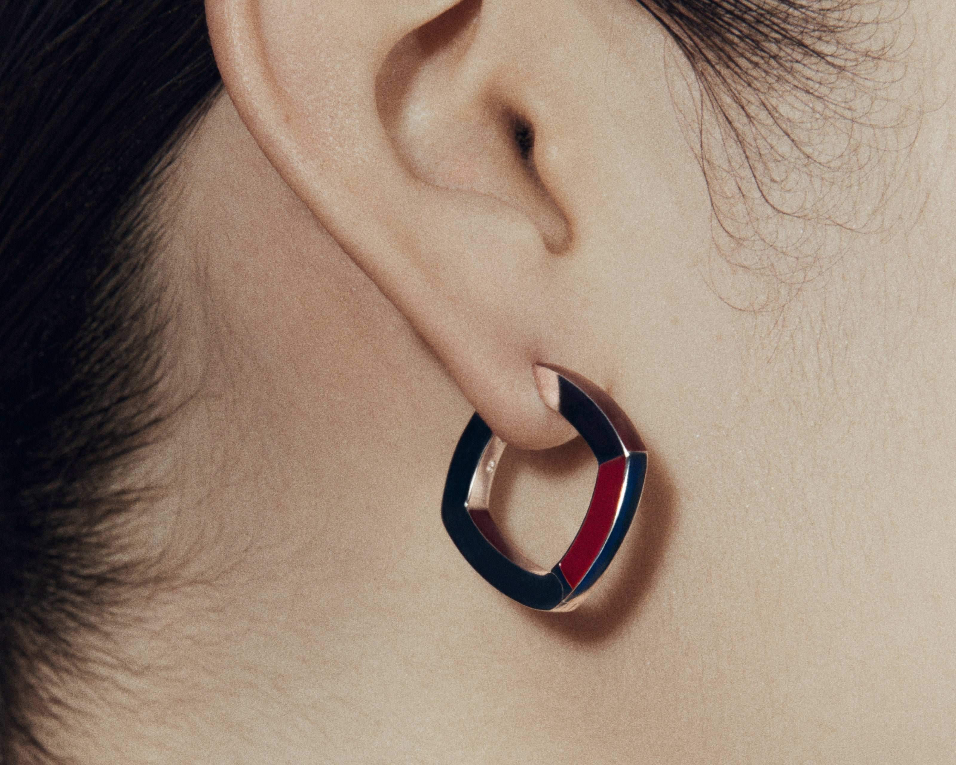 Close up of Şener Besim burgundy enamel hoop earring on ear — side view