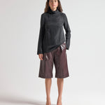 Woman wearing a black turtleneck and brown leather shorts on a white background by sener besim