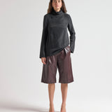 Woman wearing a black turtleneck and brown leather shorts on a white background by sener besim