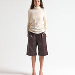 Woman wearing a beige blouse and brown leather shorts on a white background by sener besim