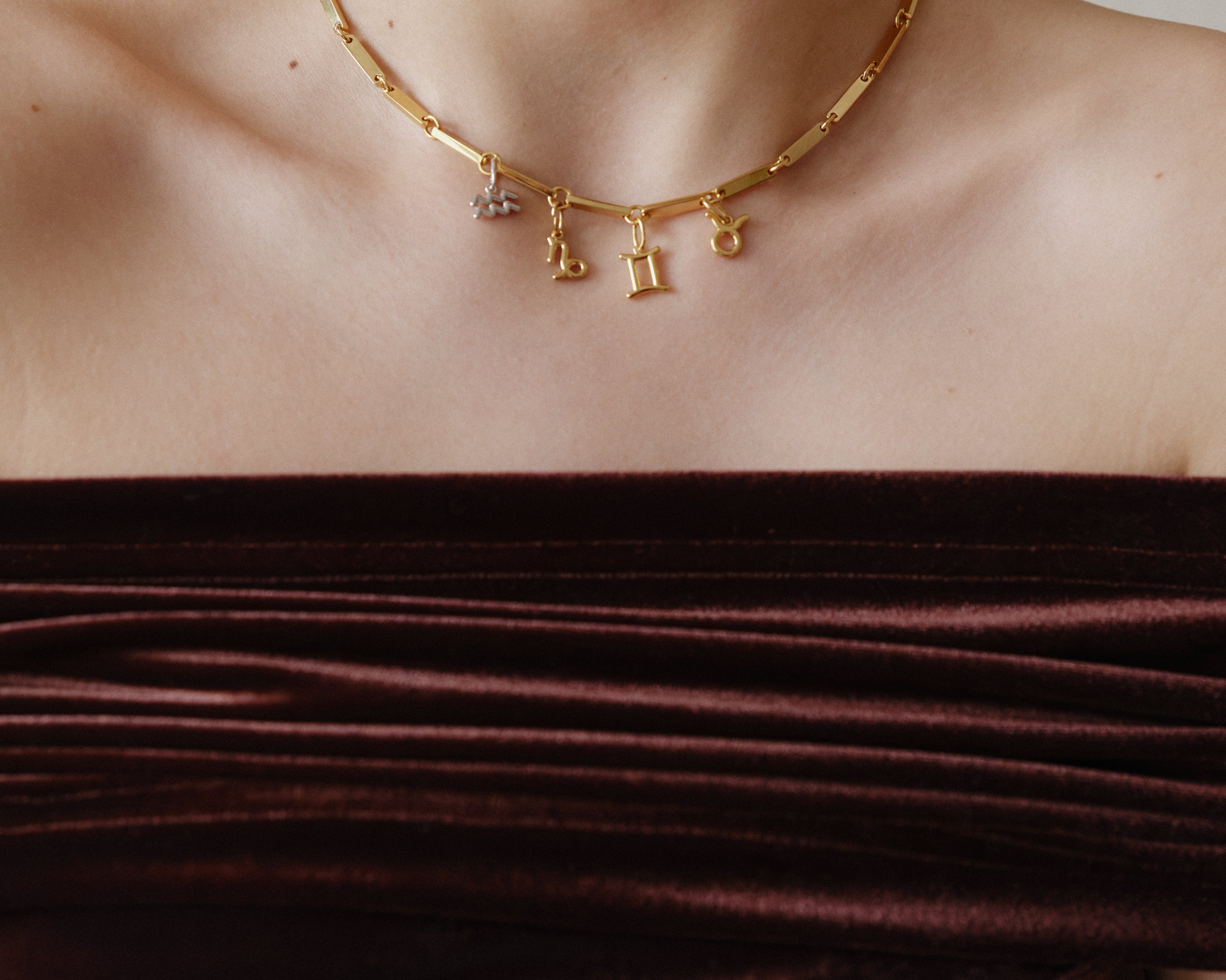 Şener Besim Horoscope Charms in gold, worn layered on chain necklace