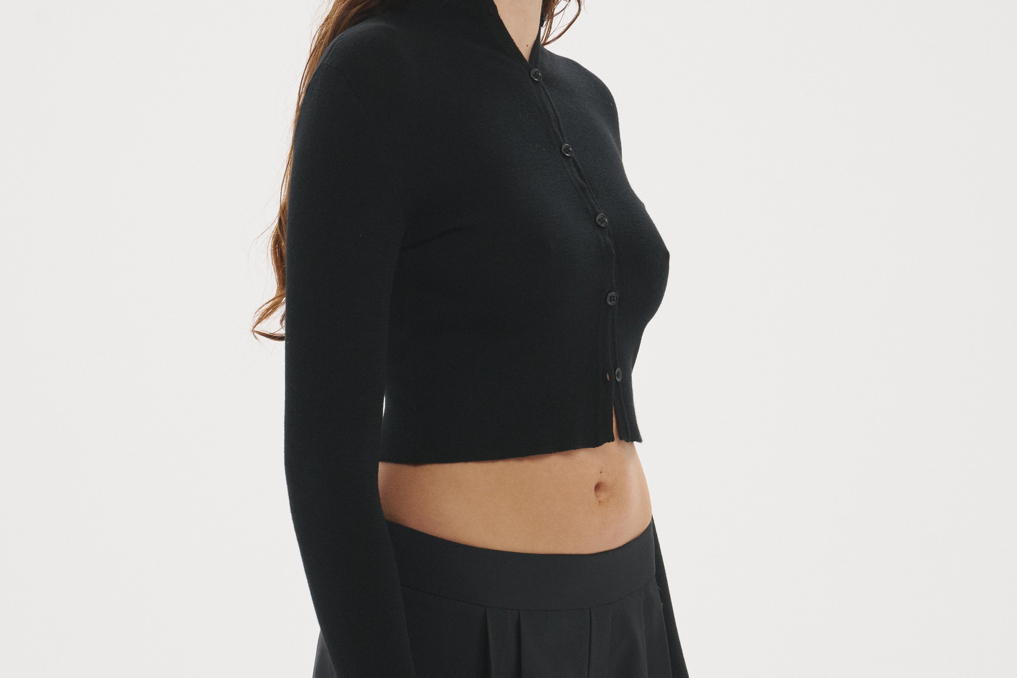 Şener Besim Multibutton Cardi in Black, side profile showing the fitted silhouette