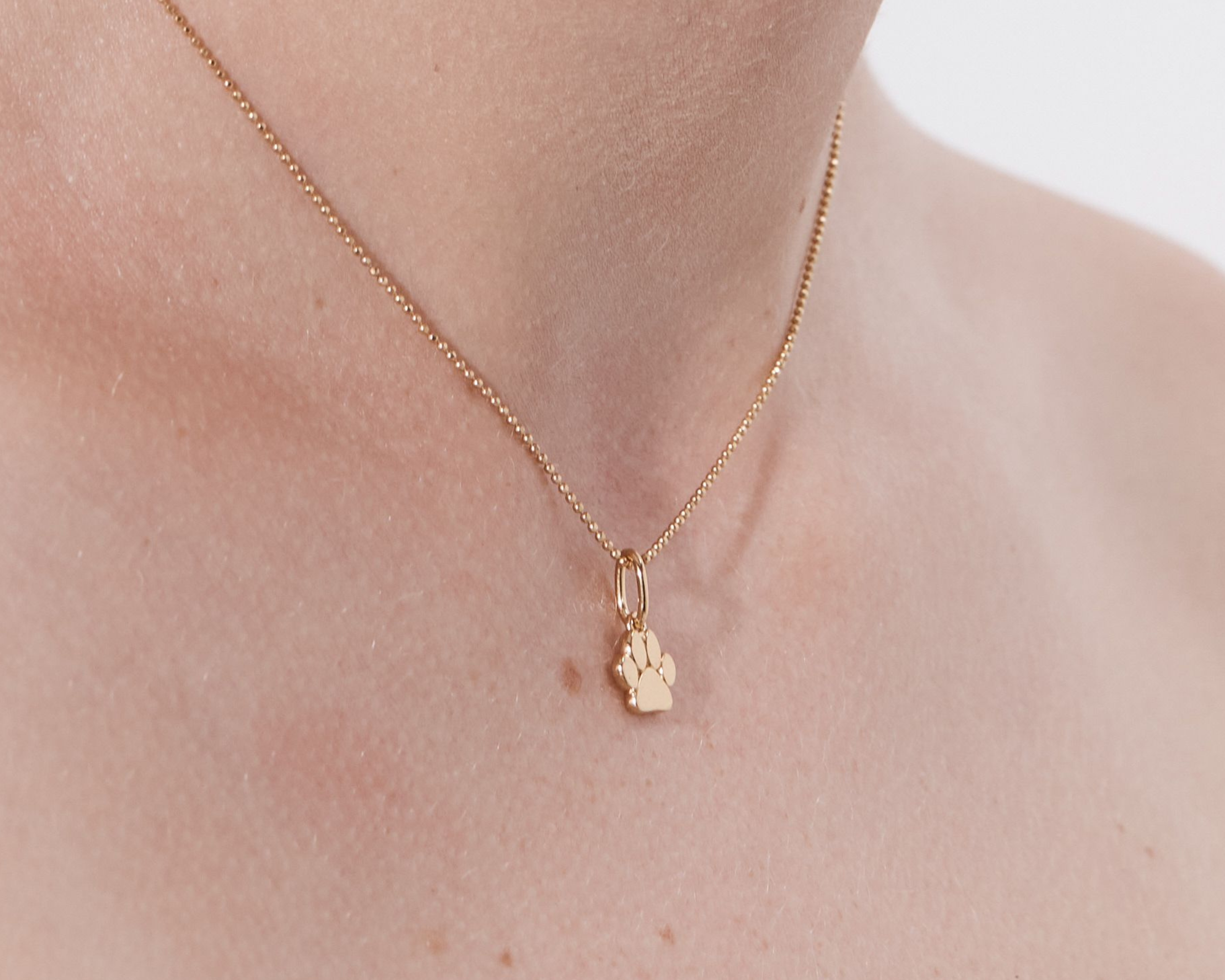 Şener Besim Paw Print Charm worn as a necklace pendant in gold plating