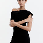 A model wearing a black mini dress with a high, structured neckline, cap sleeves, side ruching, and an exposed zipper at the back.