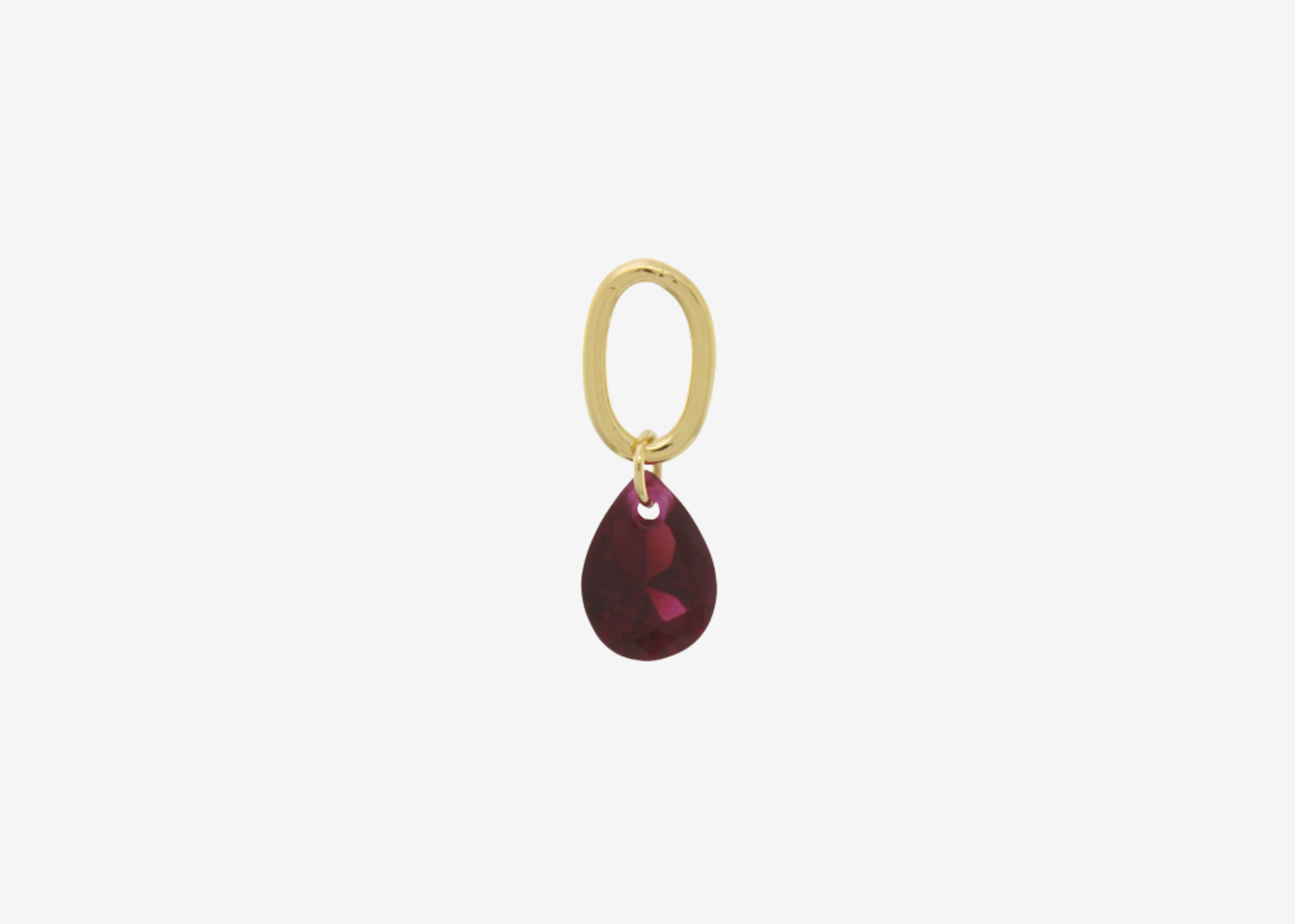 Şener Besim Teardrop Charm with garnet cubic zirconia in gold plating, flat lay