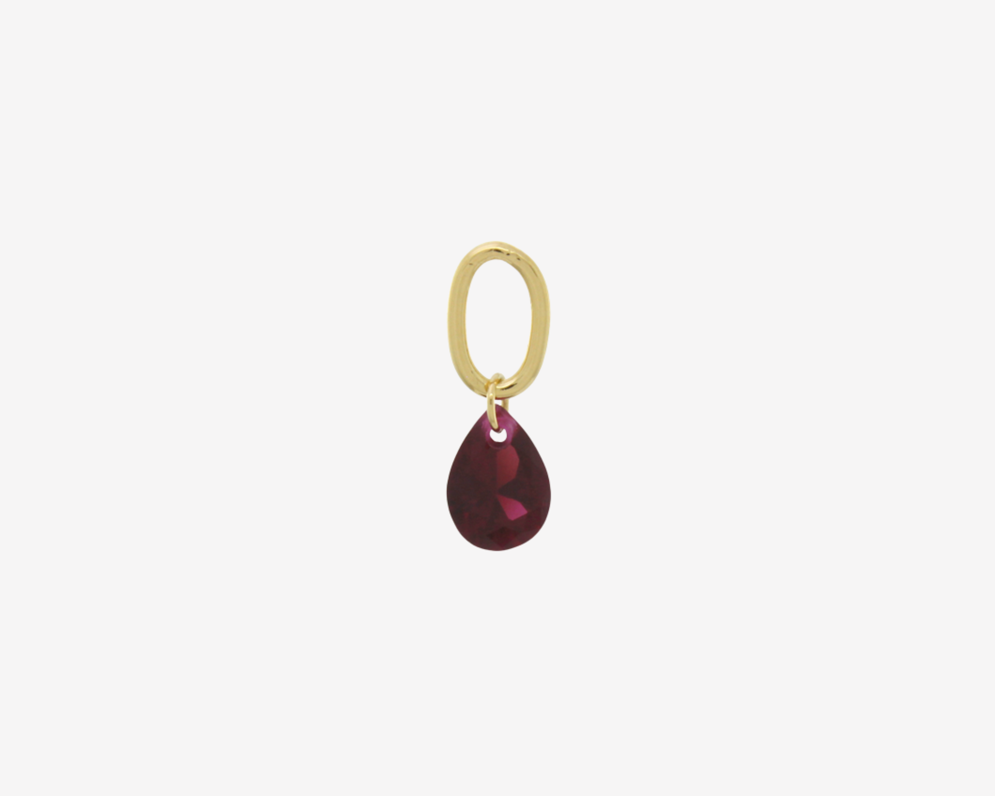 Şener Besim Teardrop Charm with garnet cubic zirconia in gold plating, flat lay