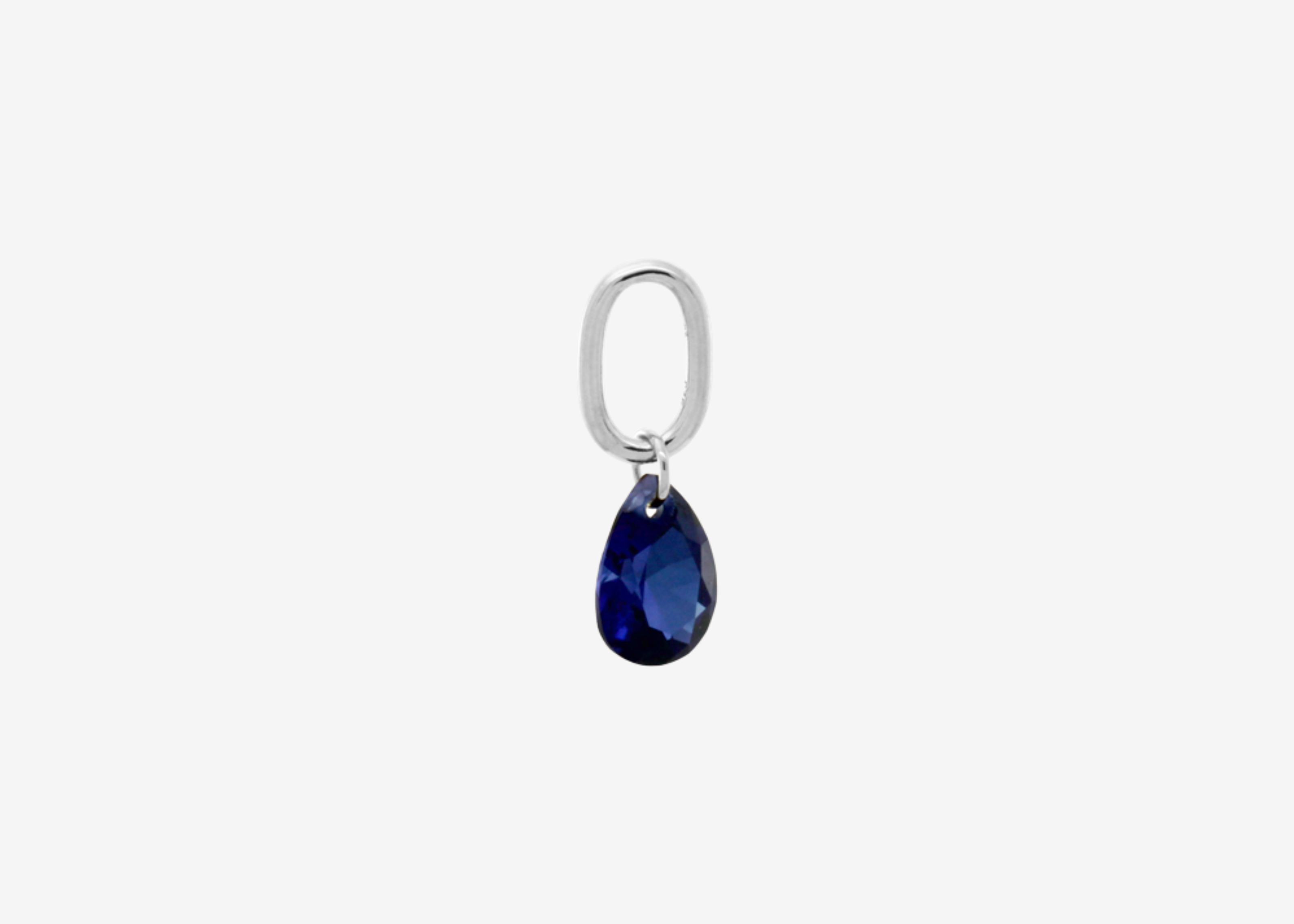 Şener Besim Teardrop Charm with sapphire cubic zirconia in rhodium plating, flat lay