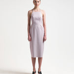 model wearing a pale pink sleeveless dress with an apron-front silhouette and an open back with two sets of ties by sener besim