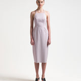 model wearing a pale pink sleeveless dress with an apron-front silhouette and an open back with two sets of ties by sener besim