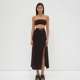 A model wearing a midi-length black skirt with extra-long ties and a split detail at the mid-thigh. The skirt is made from mercerised Turkish cotton by sener besim