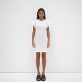 model wearing a white mini dress with an open back detail and cap sleeve by sener besim