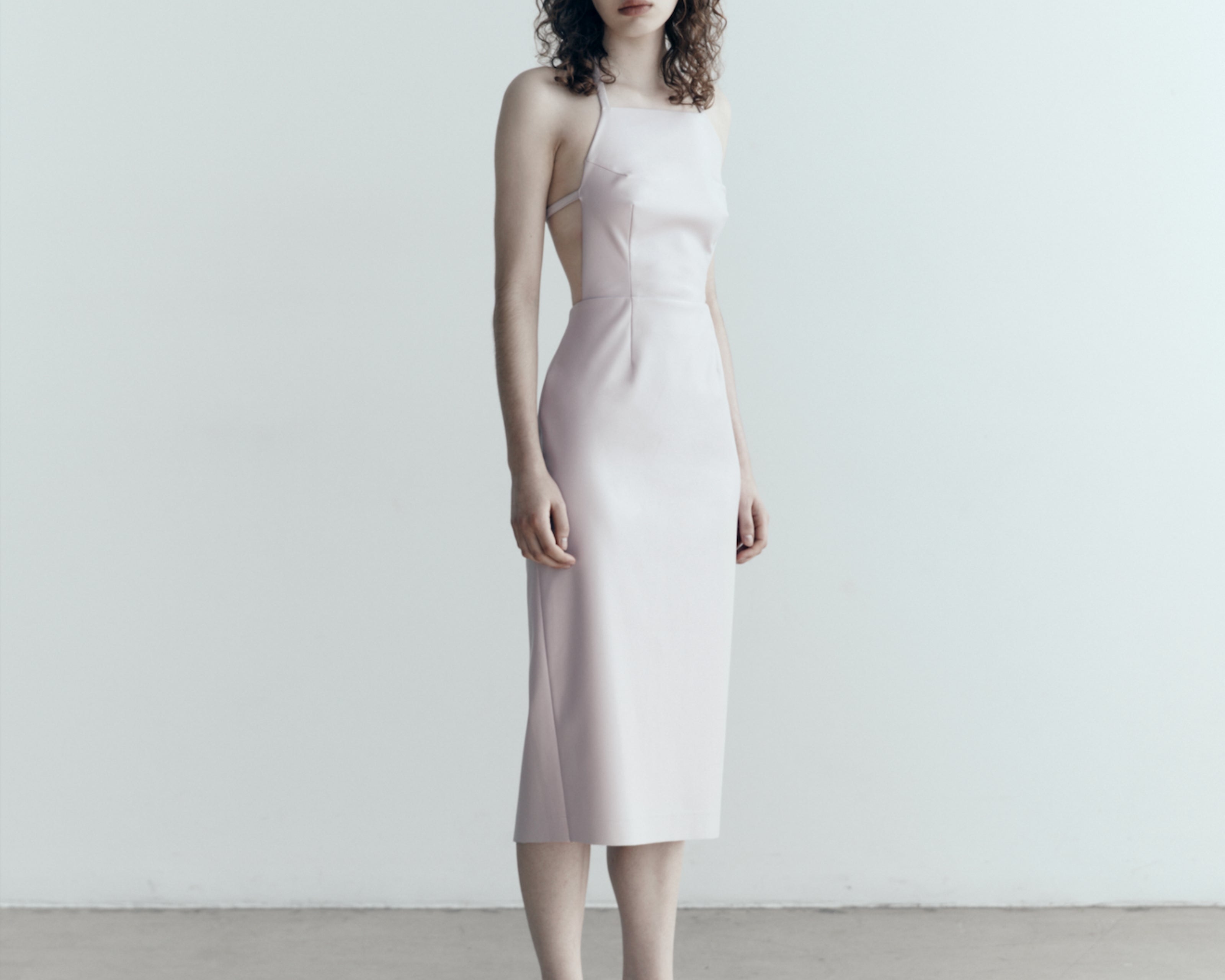 model in sener besim apron style dress with ties in pale pink