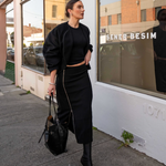 model wearing mid length zip detail skirt standing on a street with 'Sener Besim' branding.