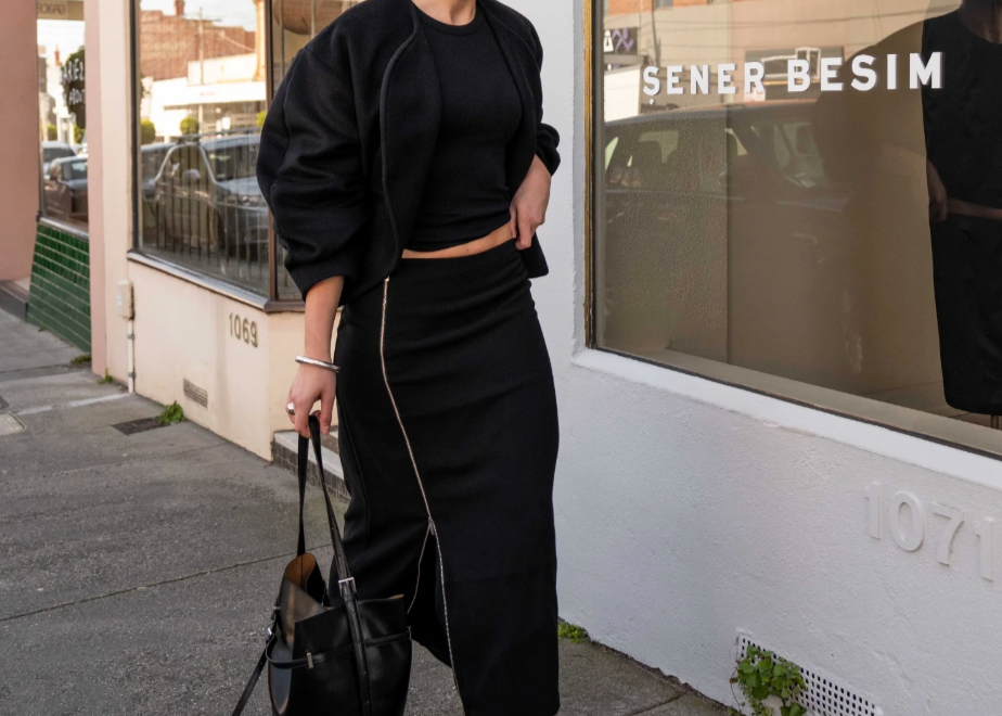 model wearing mid length zip detail skirt standing on a street with 'Sener Besim' branding.