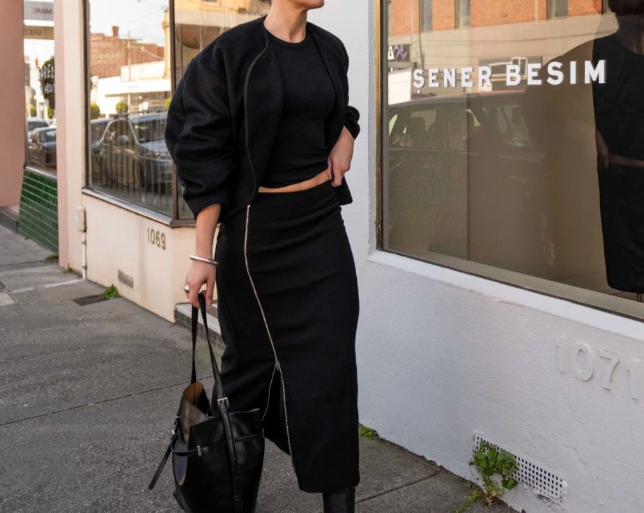 model wearing mid length zip detail skirt standing on a street with 'Sener Besim' branding.