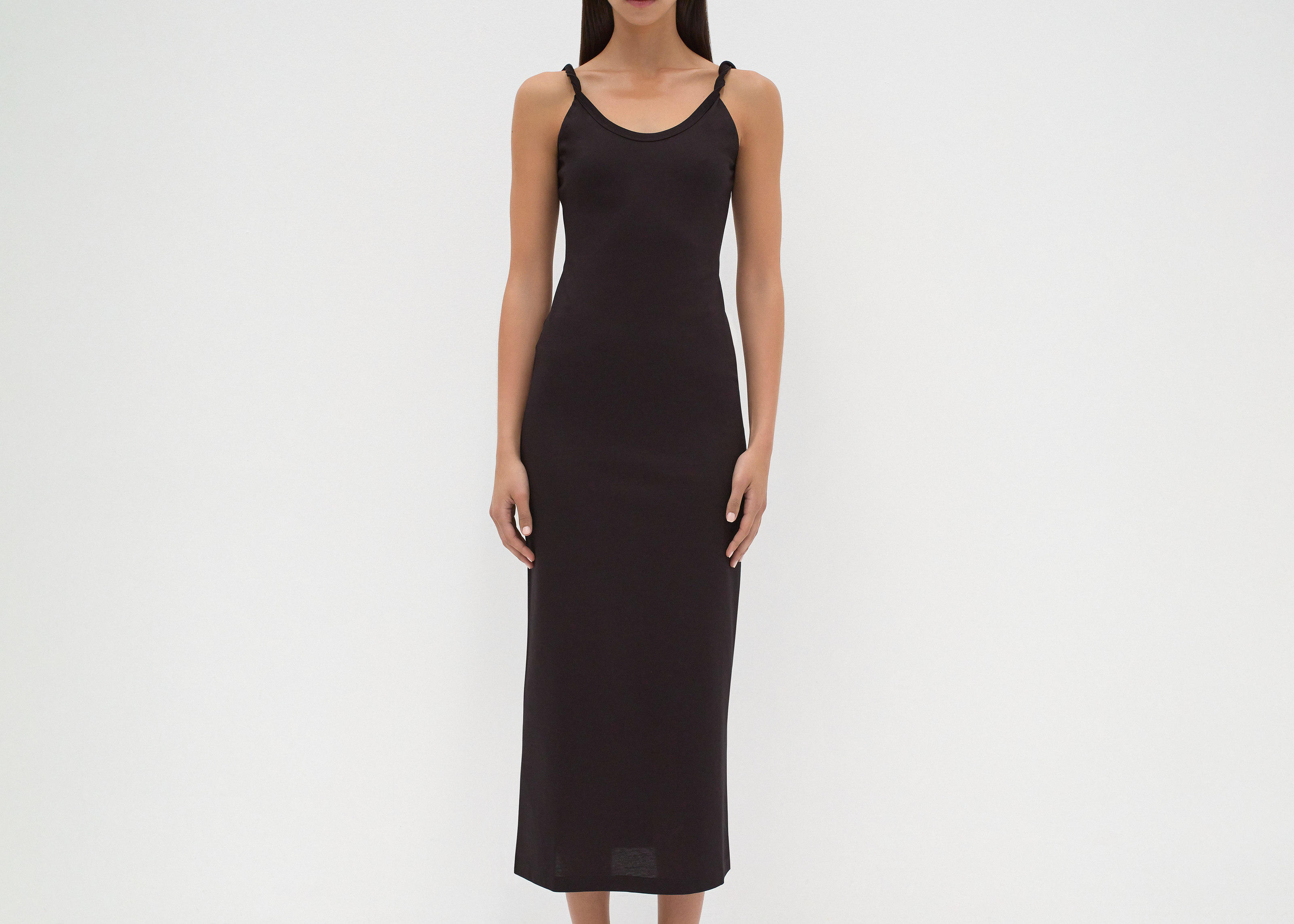 A model wearing a mid-calf length black dress with twisted strap features by sener besim