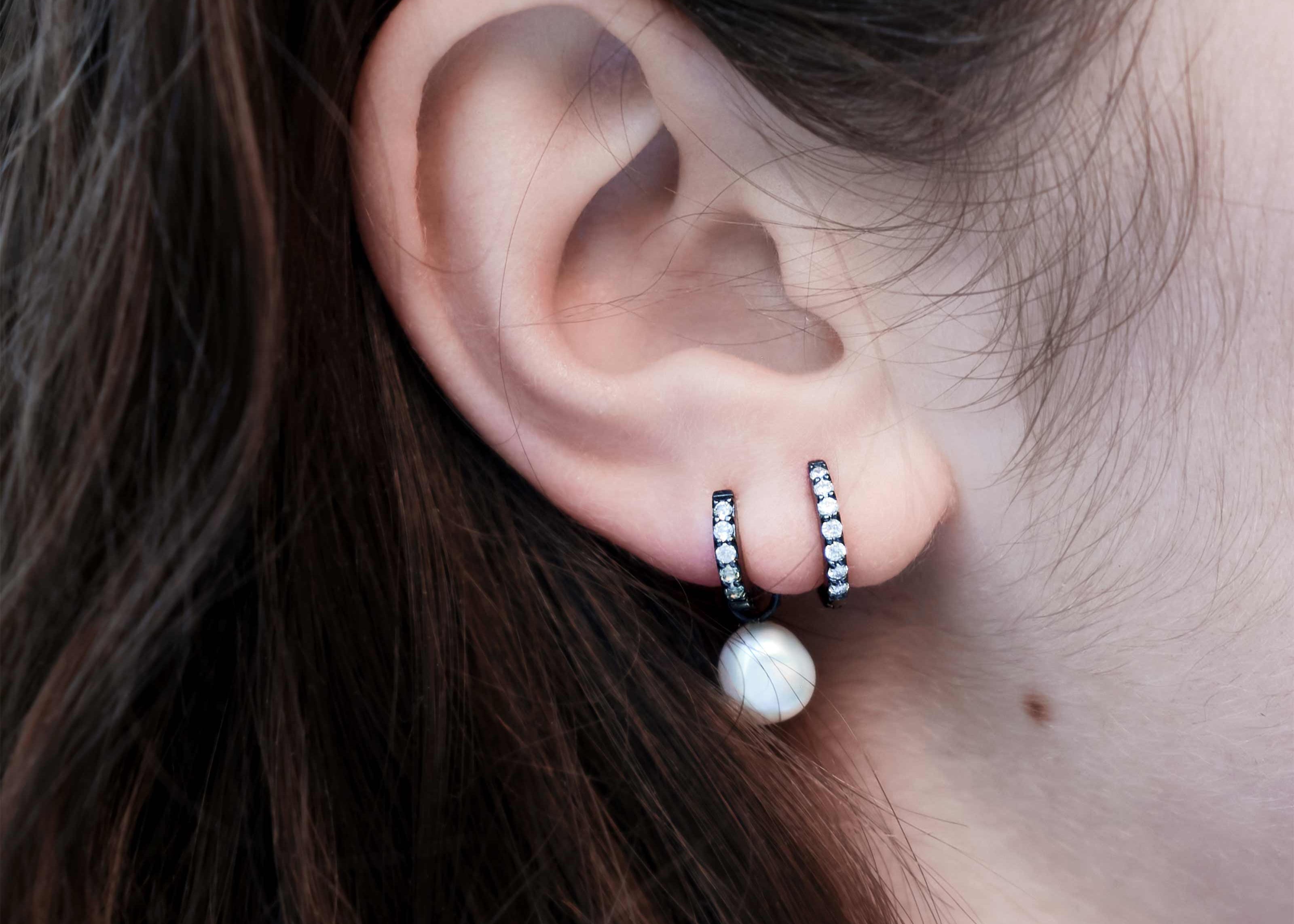 Şener Besim Black Rhodium White Diamond Medium Huggie worn on ear, sterling silver