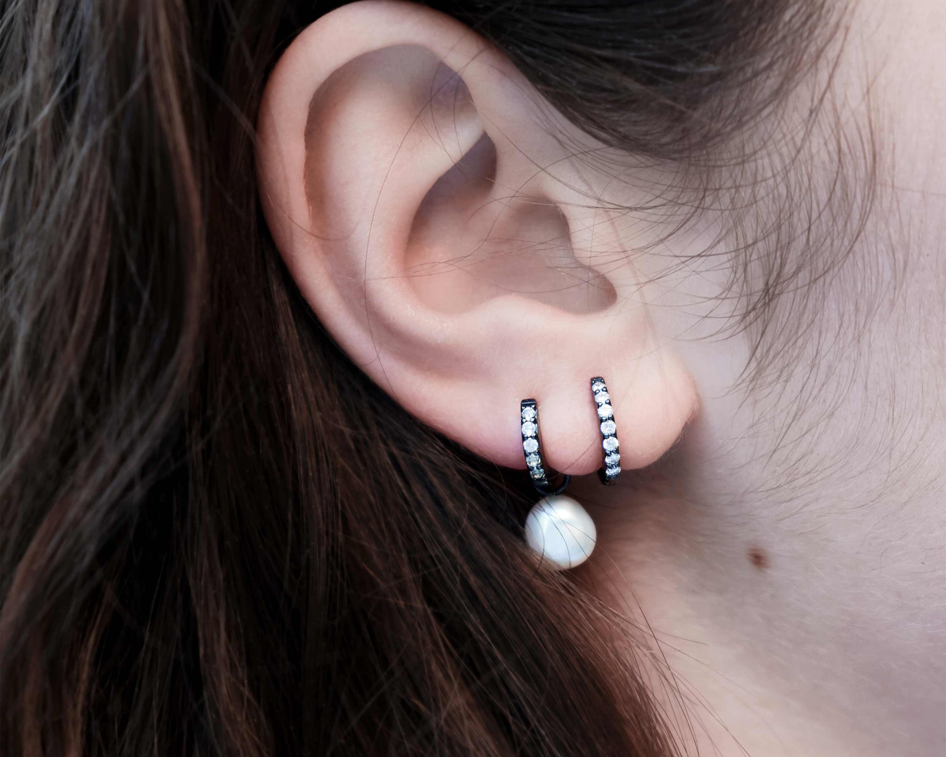 Şener Besim Black Rhodium White Diamond Medium Huggie worn on ear, sterling silver