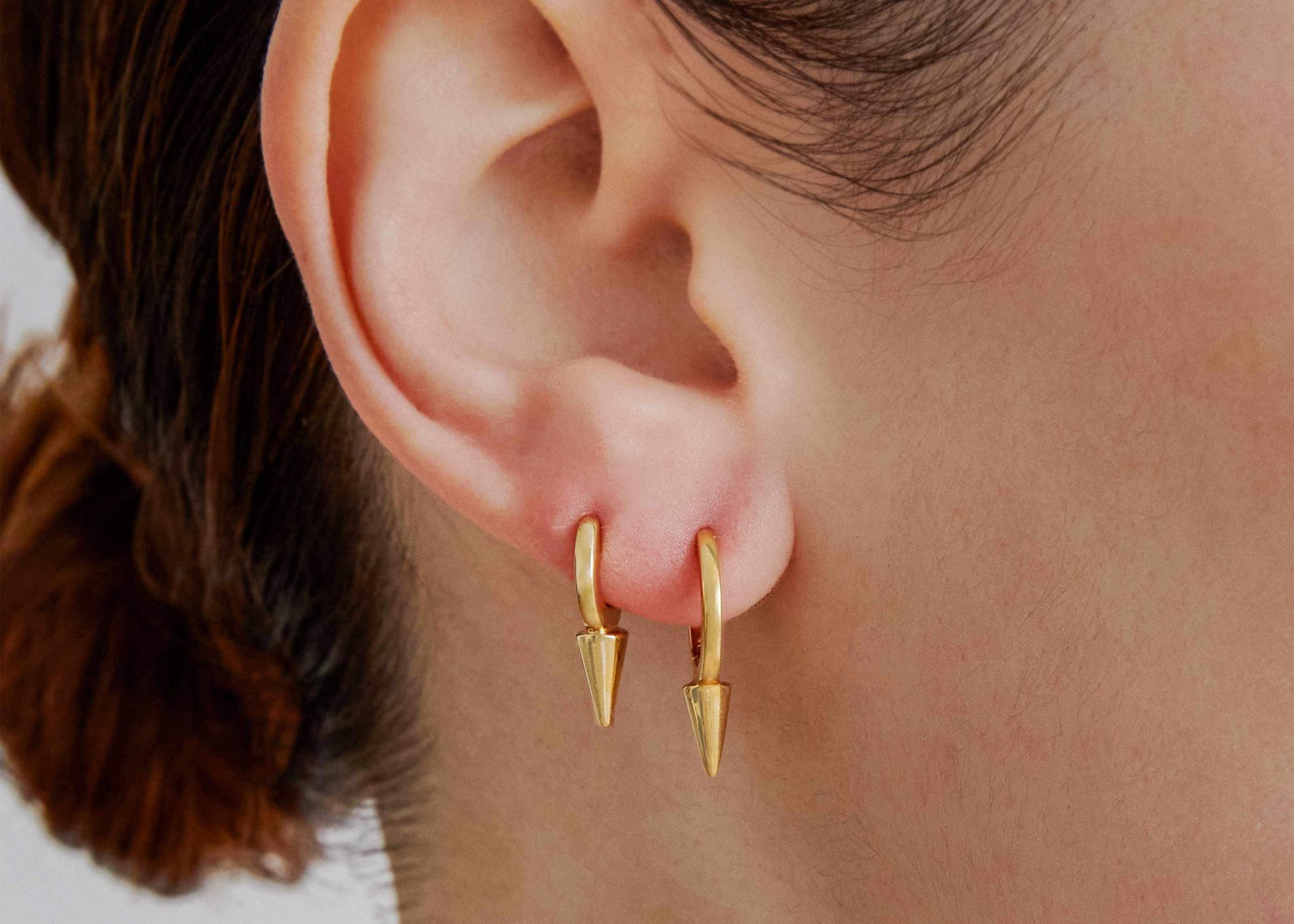 Şener Besim Medium Single Point Huggies in 14ct gold plating, worn close up on ear