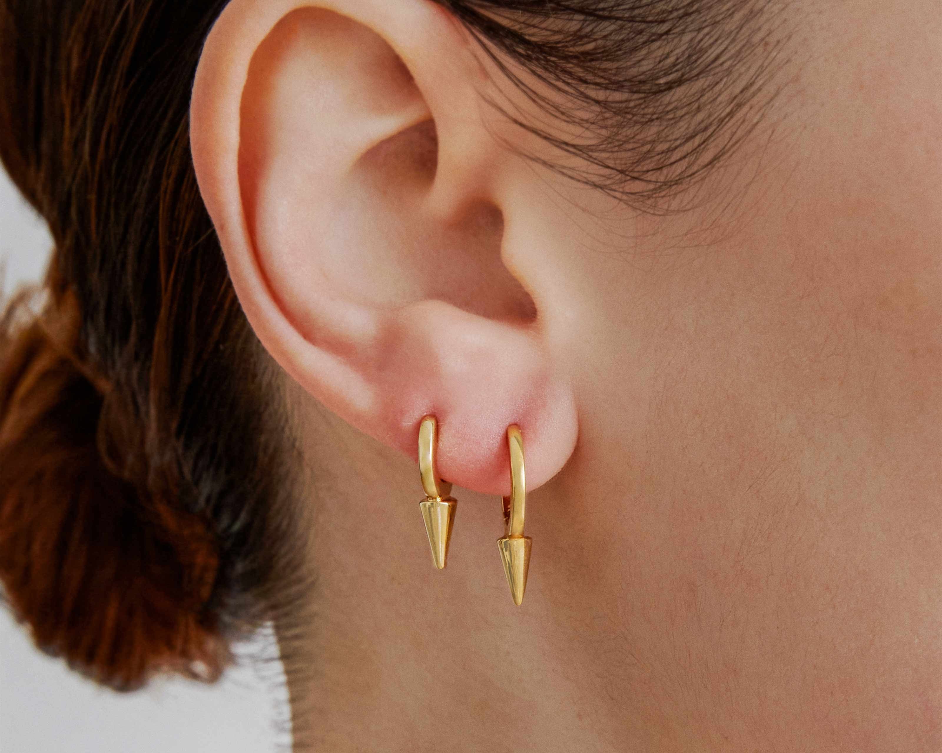 Şener Besim Medium Single Point Huggies in 14ct gold plating, worn close up on ear