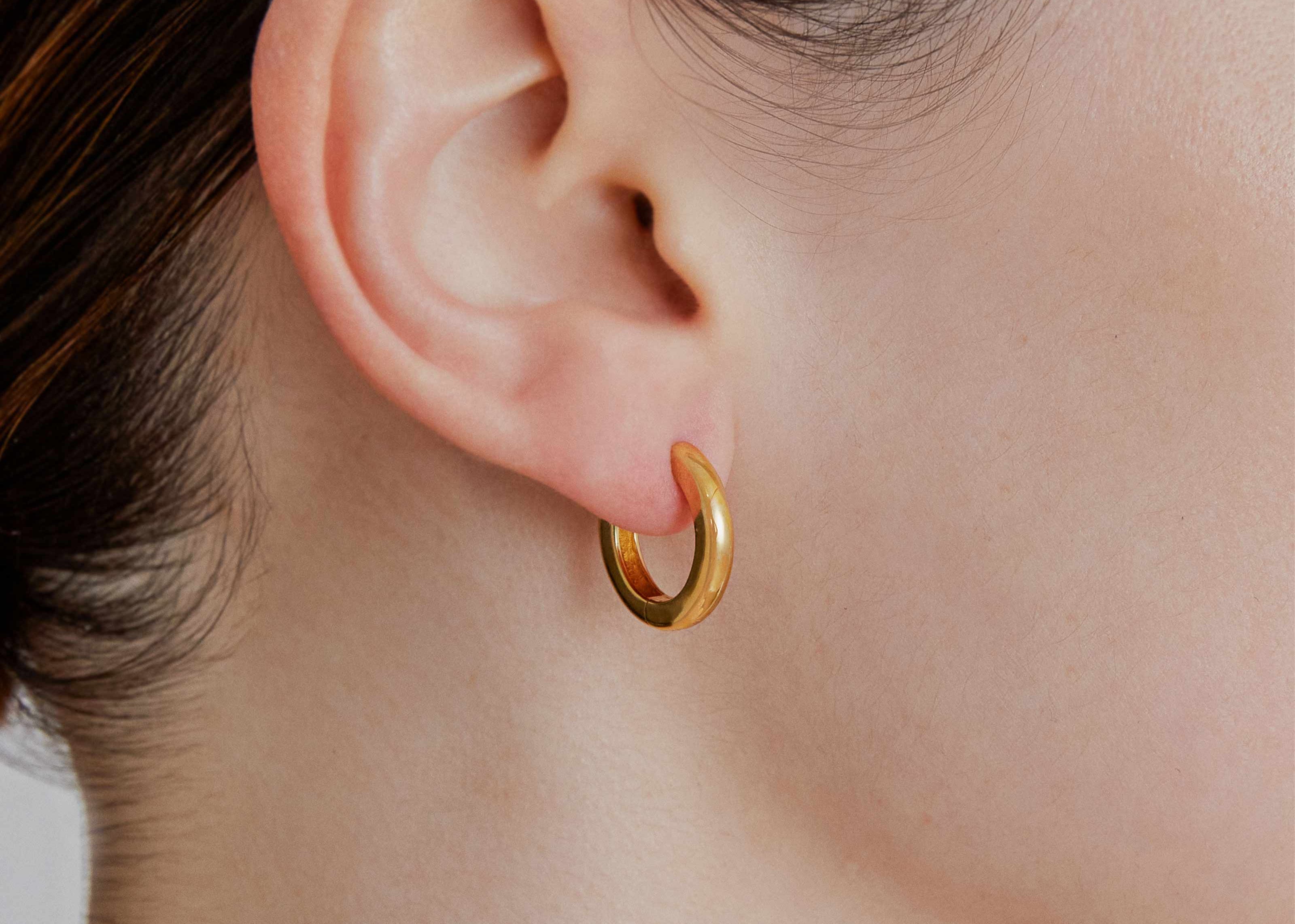 Medium gold huggie hoop earrings worn — Şener Besim Tube Series
