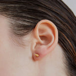 Single point spike stud earrings in gold worn on ear — Şener Besim