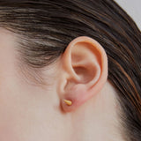 Single point spike stud earrings in gold worn on ear — Şener Besim