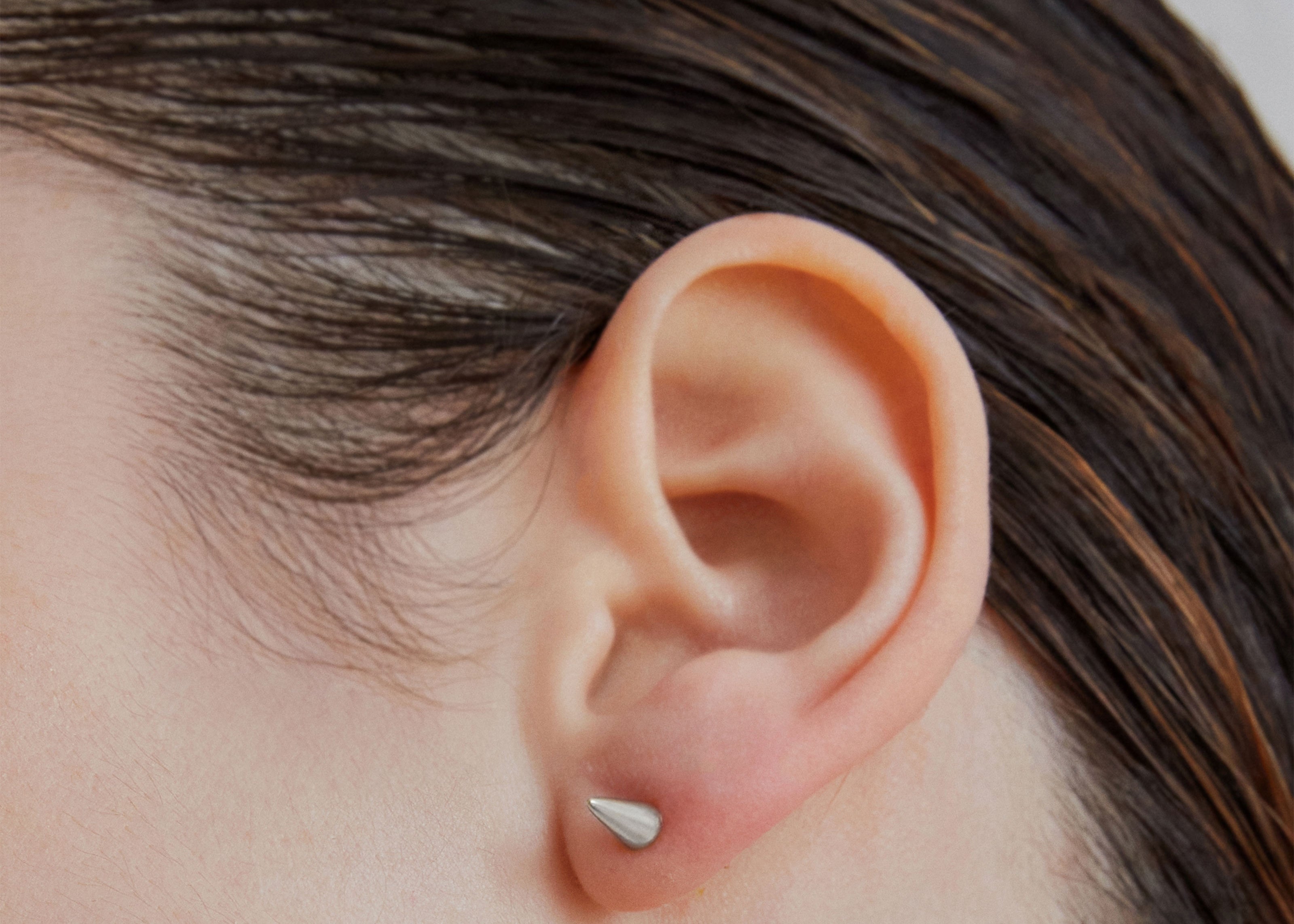 Single point spike stud earrings in silver worn on ear — Şener Besim