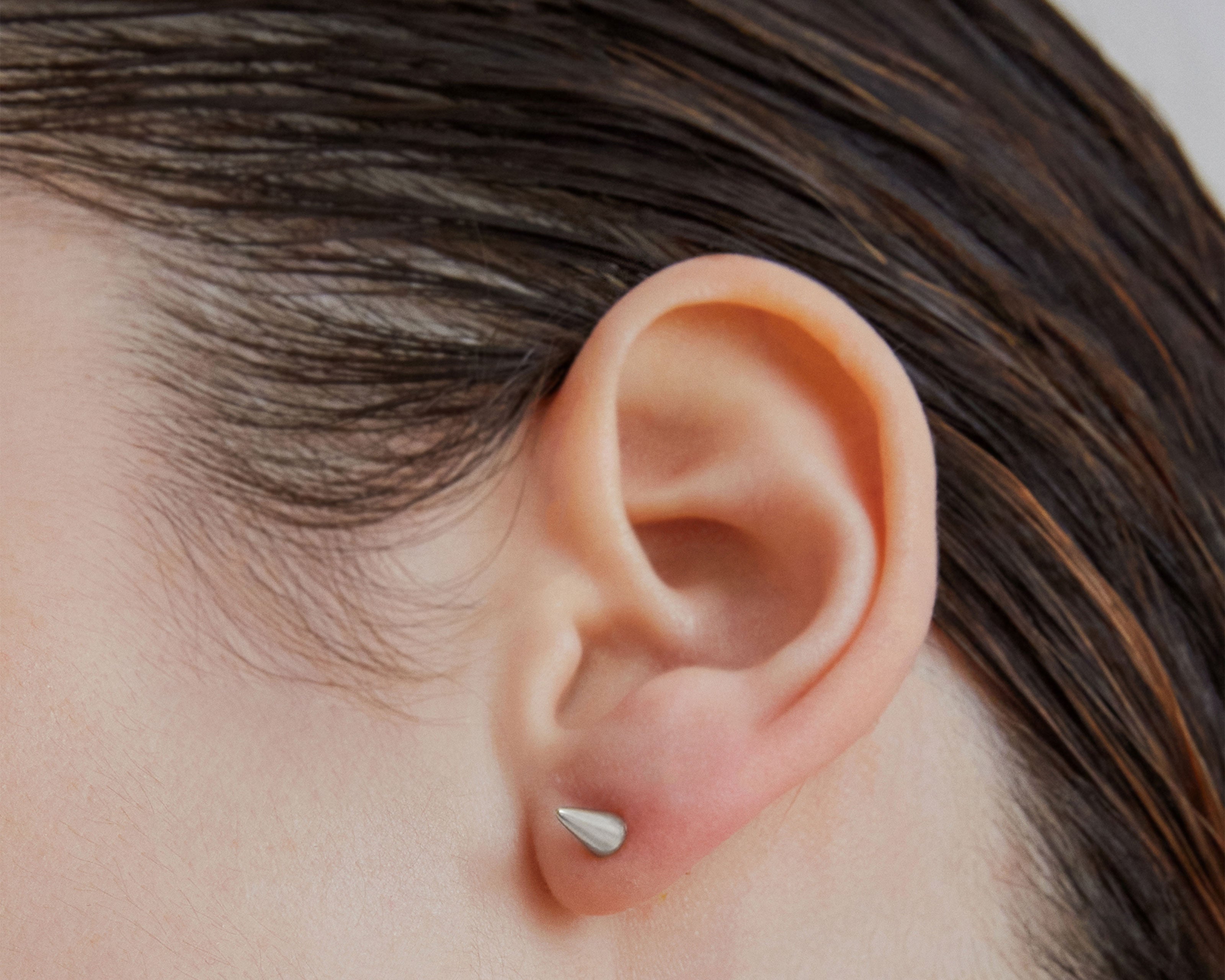 Single point spike stud earrings in silver worn on ear — Şener Besim