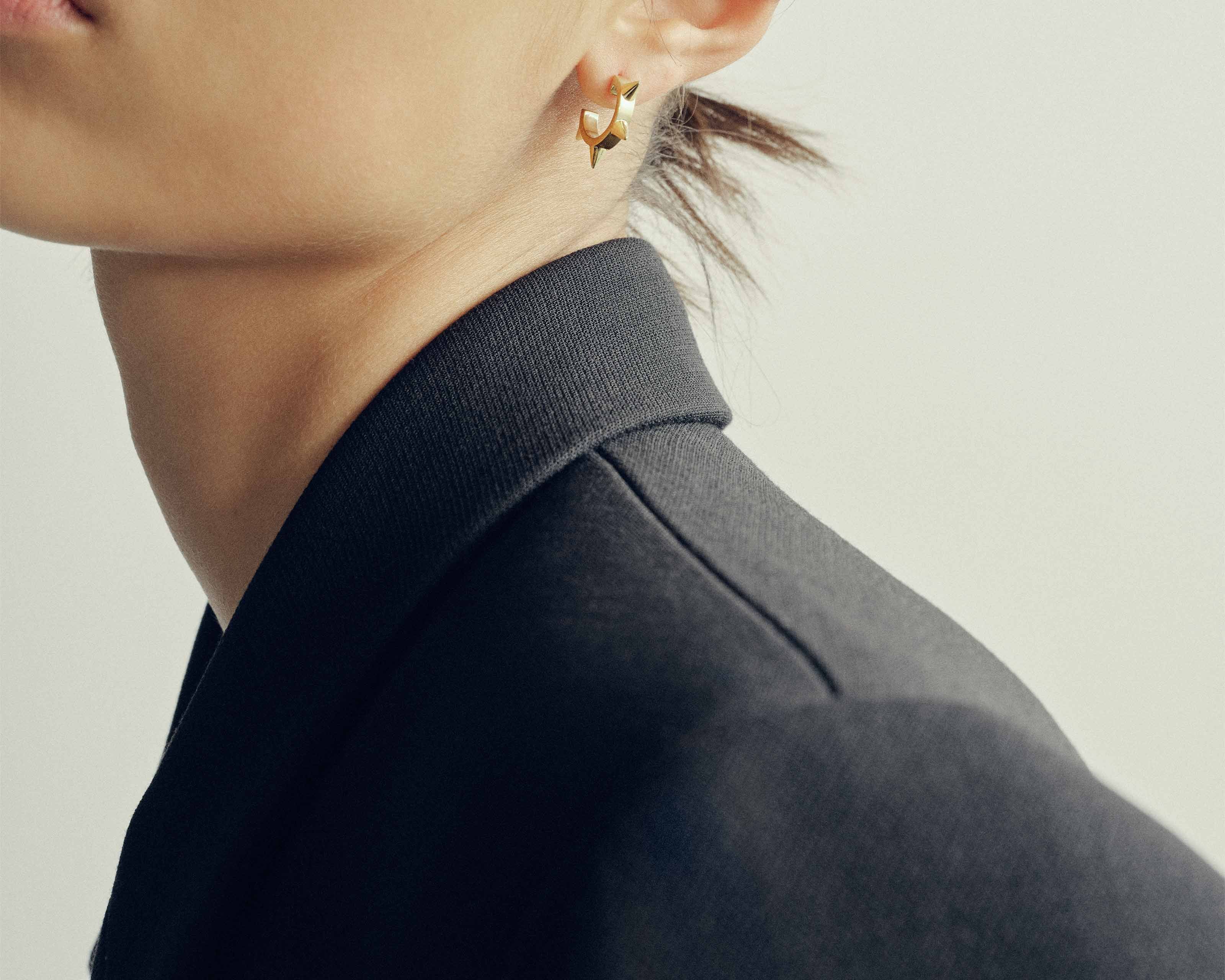 model wearing sener besim spike detailed earrings in gold